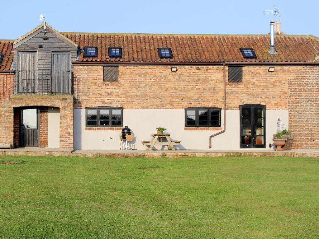a brick building with a picnic table in a yard at Mullins Cottage in Gristhorpe