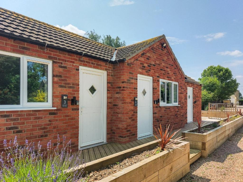 a brick house with white doors and a wooden deck at Tupholme - Uk49436 in Walcot