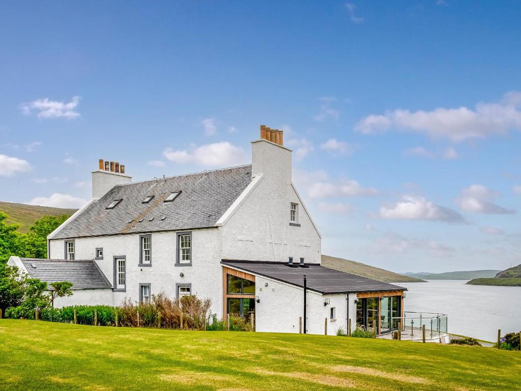 a large white house with a large grass yard at Voe House in Voe
