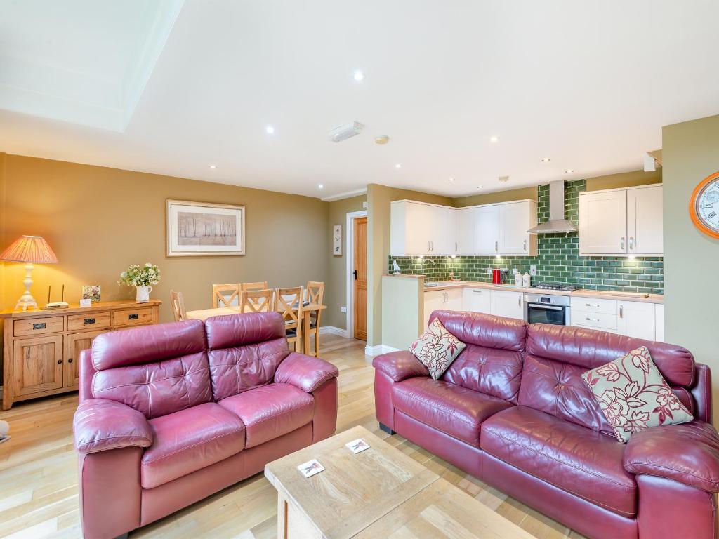 een woonkamer met 2 leren banken en een keuken bij Oak Cottage in Ware