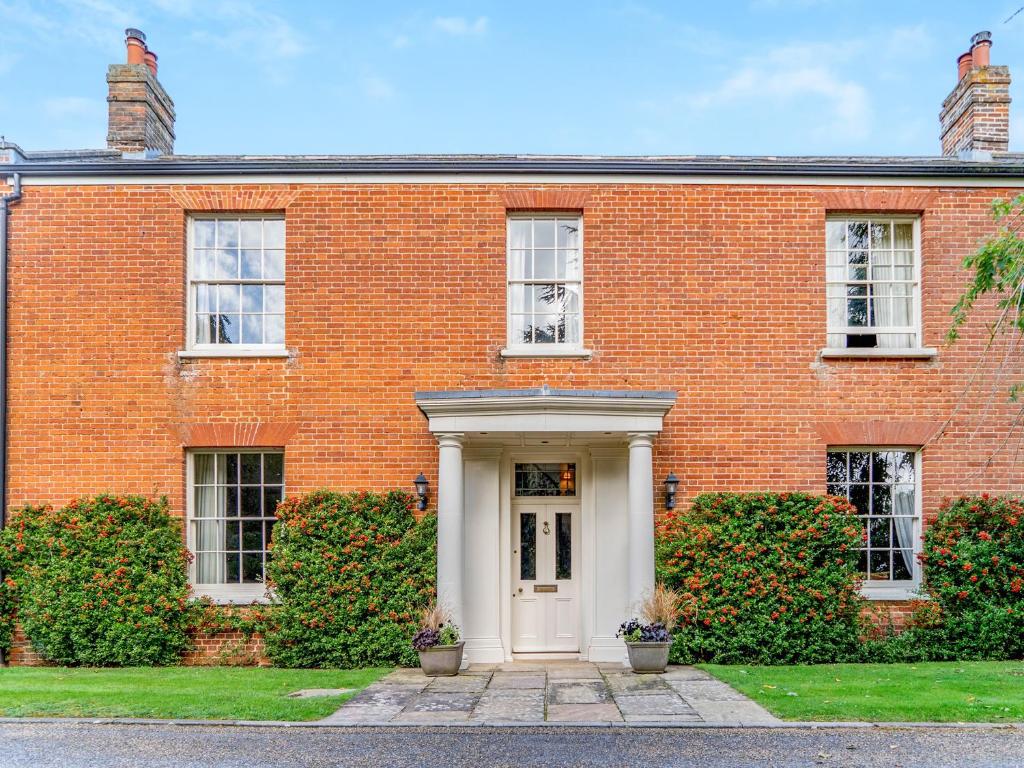 una casa de ladrillo rojo con puerta blanca en The Grange Farmhouse, en Sculthorpe