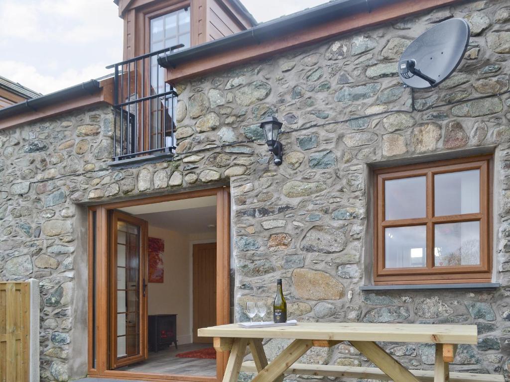a stone building with a wooden table in front of it at Ysgubor Myfi - Uk6001 in Bodedern