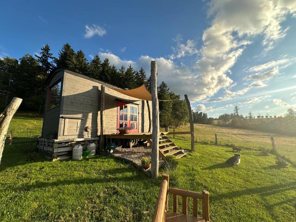 a tiny house in a field with a fence at Maringotka Květuška ubytování na farmě in Pulečný