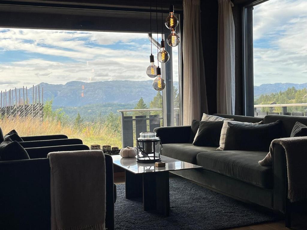 een woonkamer met banken en een groot raam bij Modern and cozy mountain cabin - panoramic view! in Torvetjørn