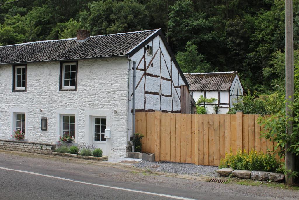 a white cottage with a wooden fence on the side of the road at Le Néblon insolite in Ouffet