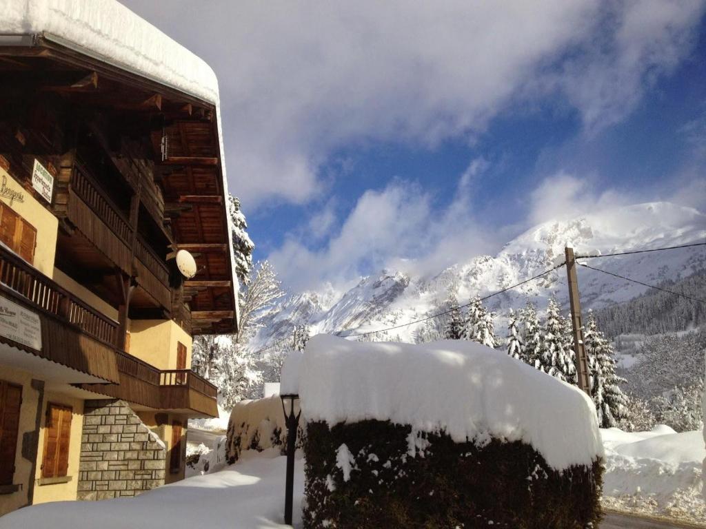 un edificio cubierto de nieve con montañas de fondo en Vieille Bergerie 2, en Le Fernuy