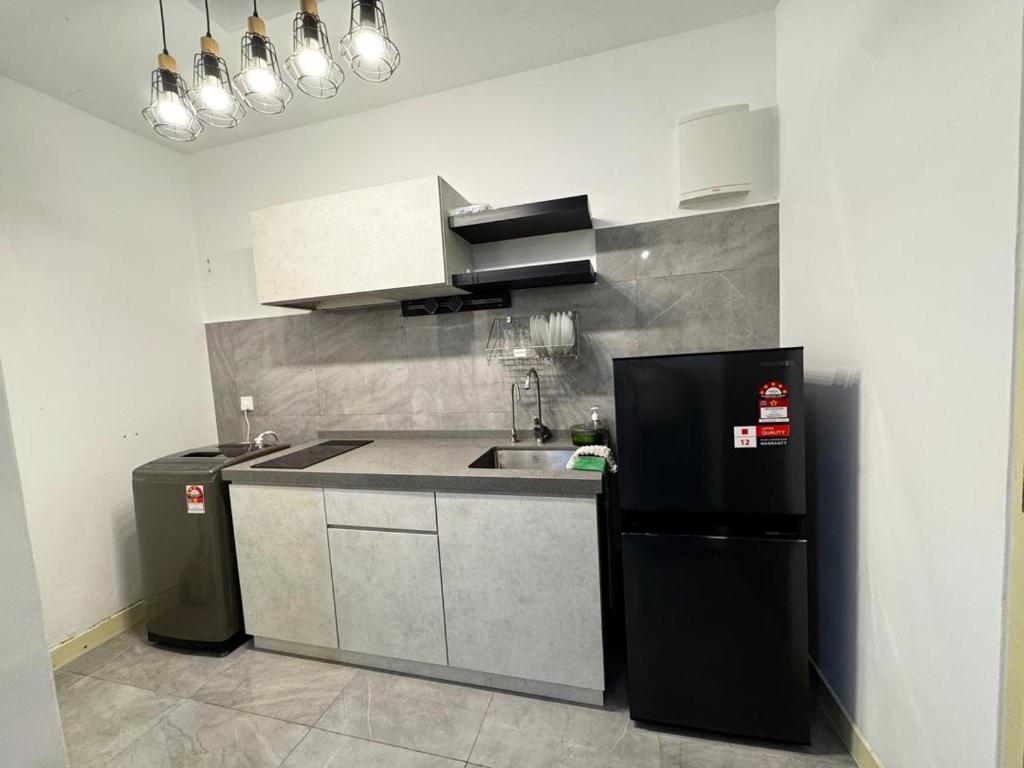 a kitchen with a sink and a black refrigerator at Imperio Studio in Malacca
