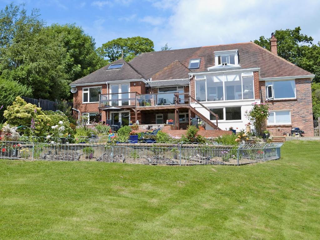a large house with a fence in the yard at The Cottage in Fairlight