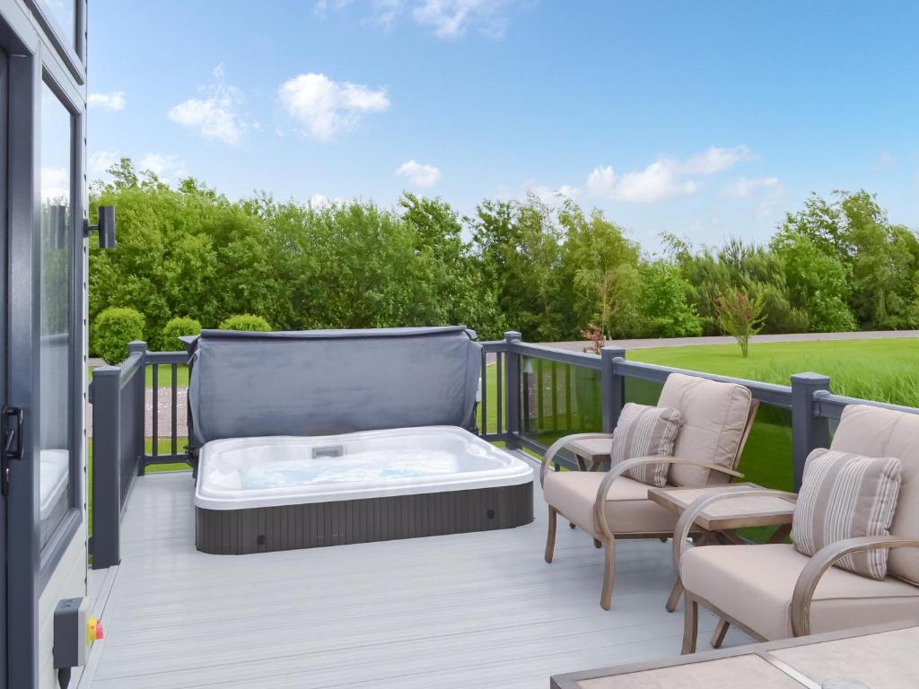 una terraza con bañera de hidromasaje y sillas en Reel Paradise - Uk37723, en Ingoldmells