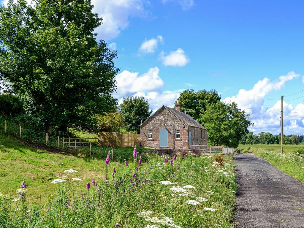 ein altes Haus auf einem Feld neben einer Straße in der Unterkunft Kingfisher Cottage in Kirkton of Airlie