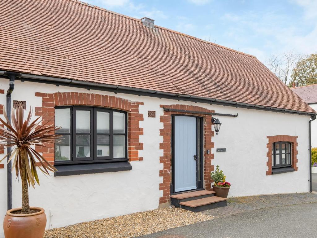 a white house with black windows and a potted plant at Celtic Retreat - Uk6721 in Lydstep