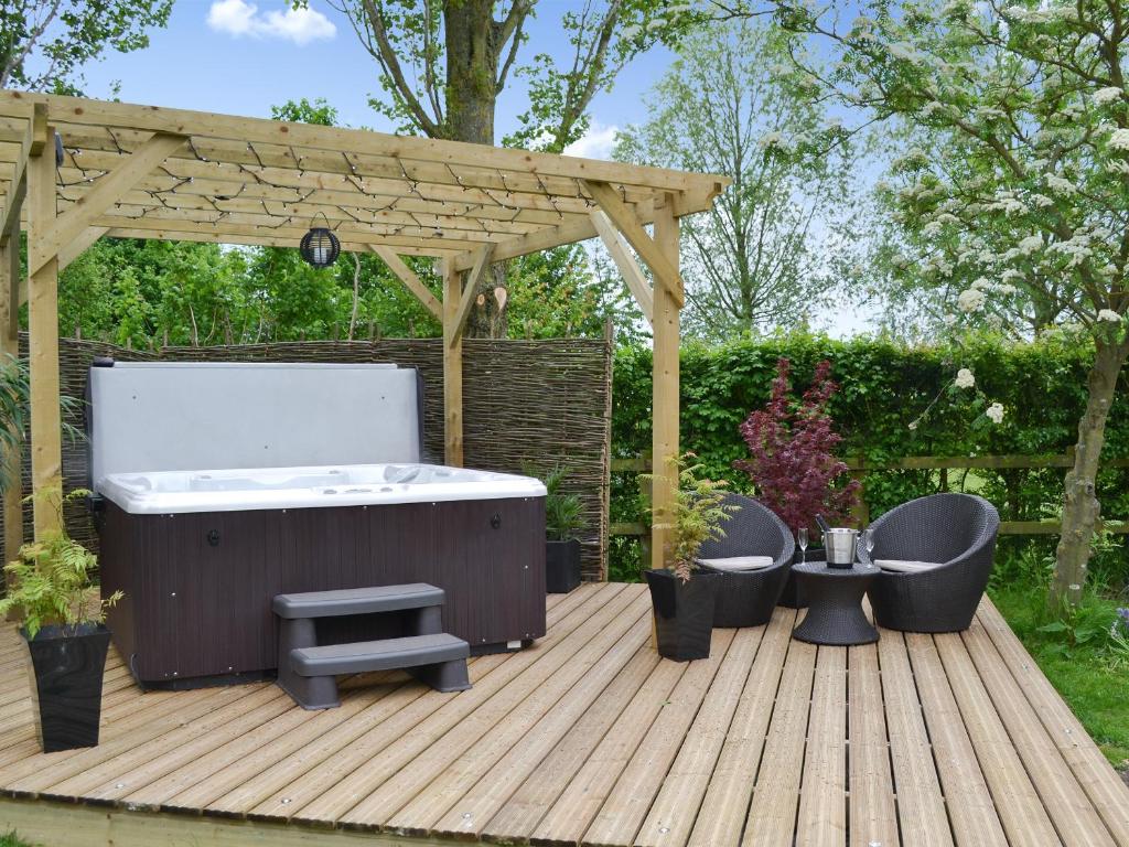 a hot tub on a wooden deck with a pergola at The Old Stables in Rickinghall
