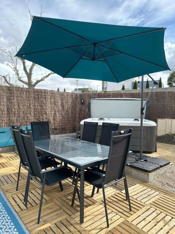 einen Tisch mit Stühlen und einen blauen Schirm auf einer Terrasse in der Unterkunft Le Nid Des Grèves avec jacuzzi in Langueux