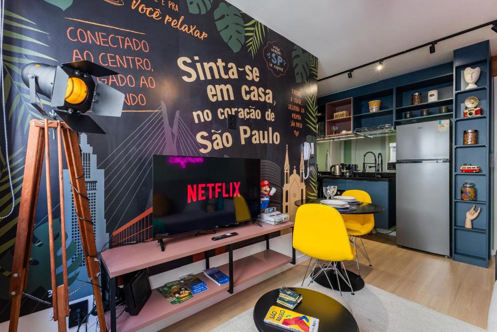 a living room with a tv and a yellow chair at PROMOÇĀO - Apartamento Gamer com Cinema e Garagem Grátis in Sao Paulo