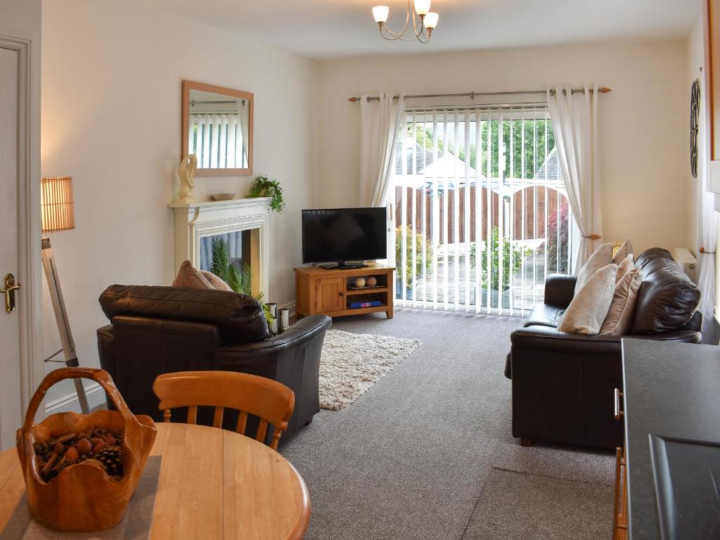 a living room with couches and a table and a tv at No 8 Harney Peak in Portinscale
