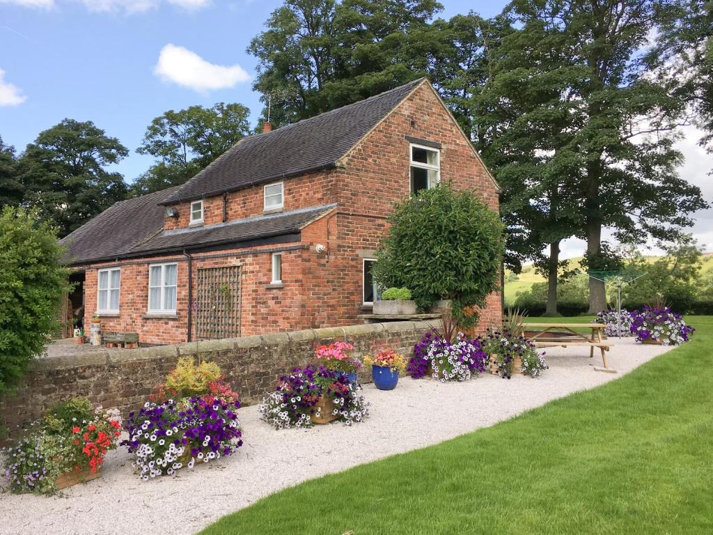 a brick house with flowers in front of it at Garden Farm Cottage in Ilam
