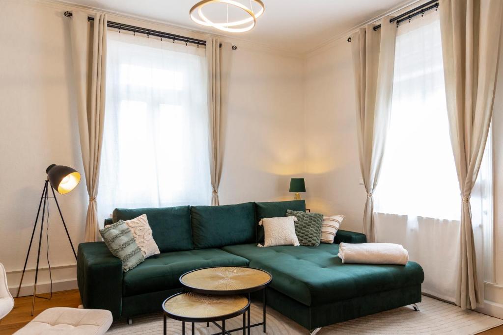 a living room with a green couch and a table at Ruhestein Quartier - Charaktervolle Wohnung perfekt für Gruppen&Familien, ideale Lage, nahe Bhf, bestens geeignet für entspannte als auch akitve Aufenthalte in malerischer Umgebung in Baiersbronn