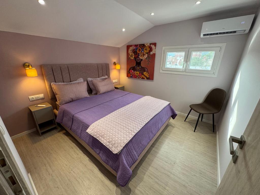 a bedroom with a purple bed and a chair at The 50 50 Deluxe Apartments in Sidari