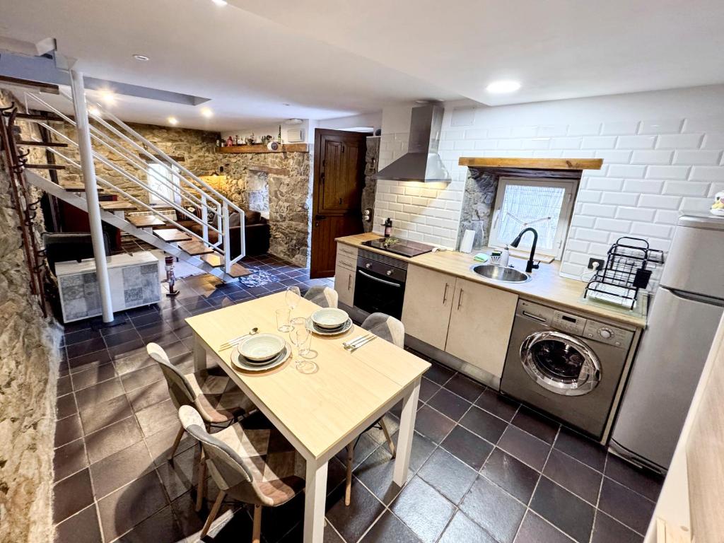 a kitchen with a table and a sink and a dishwasher at Casita con encanto, les gaites in Collanzo