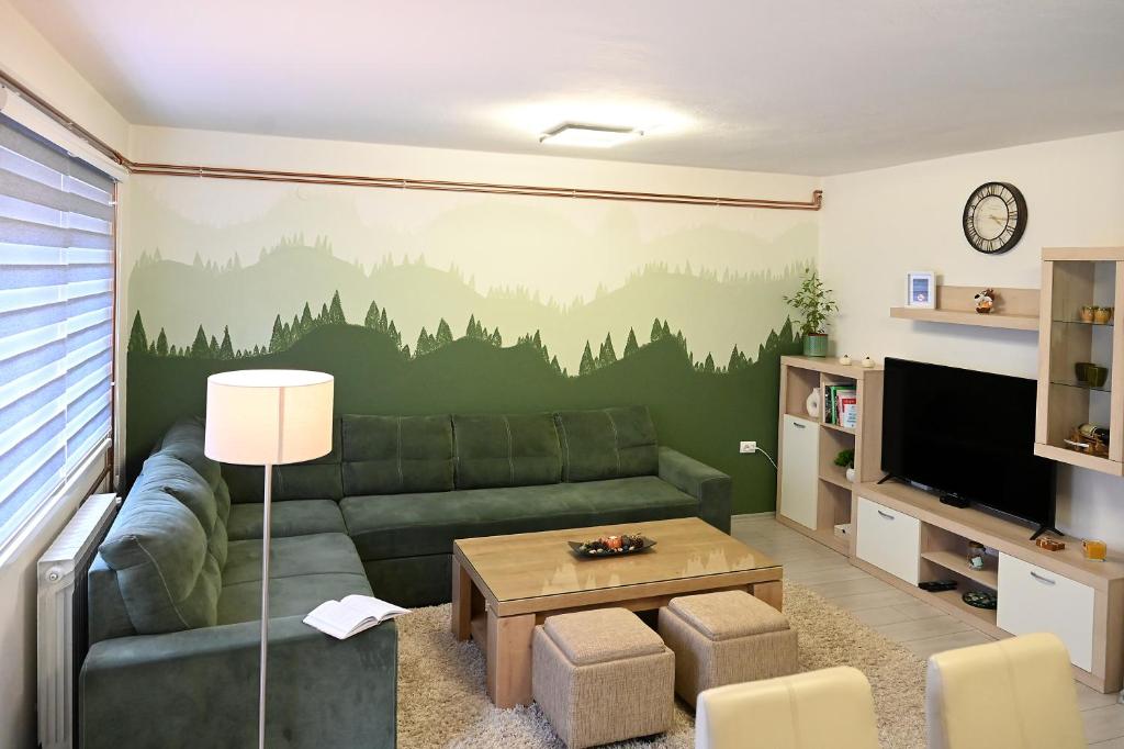 Una sala de estar con un sofá verde y una mesa. en Divas, en Pale