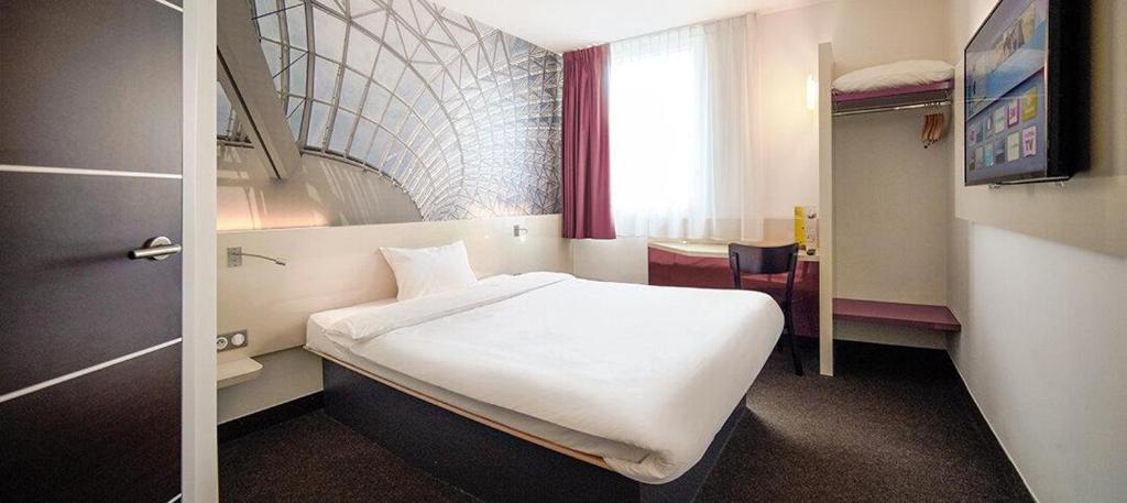 Un dormitorio con una gran cama blanca en una habitación. en B&amp;B HOTEL Katowice Centrum, en Katowice