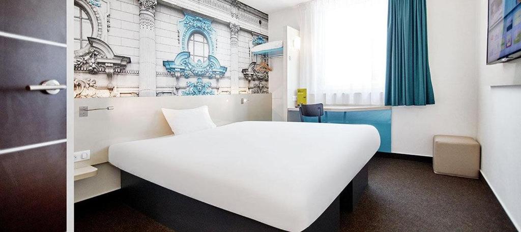 Un dormitorio con una cama blanca y una ventana. en B&amp;B Hotel Łódź Centrum, en Łódź