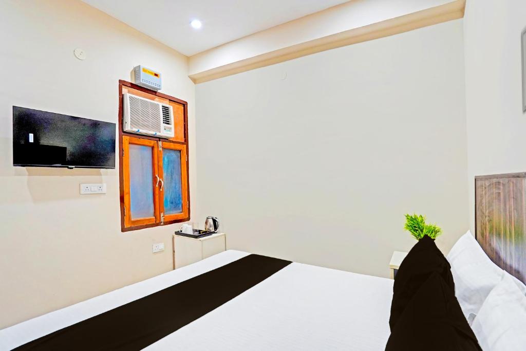 a bedroom with a bed and a tv on the wall at Hotel O Shree Jee Inn Guest House in Gurgaon