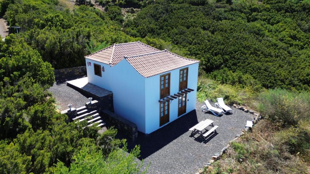 Una pequeña casa azul en una colina con dos sillas. en House Near the Stars, en Garafía