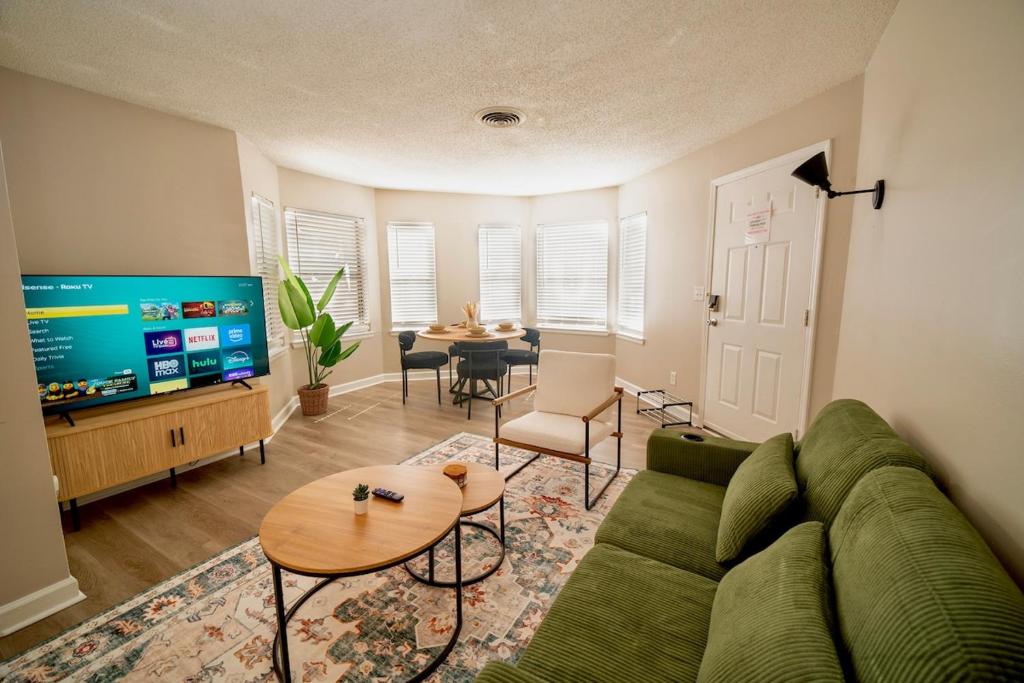 a living room with a green couch and a table at Stylish & Cozy Retreat with Backyard & Parking in Charlotte