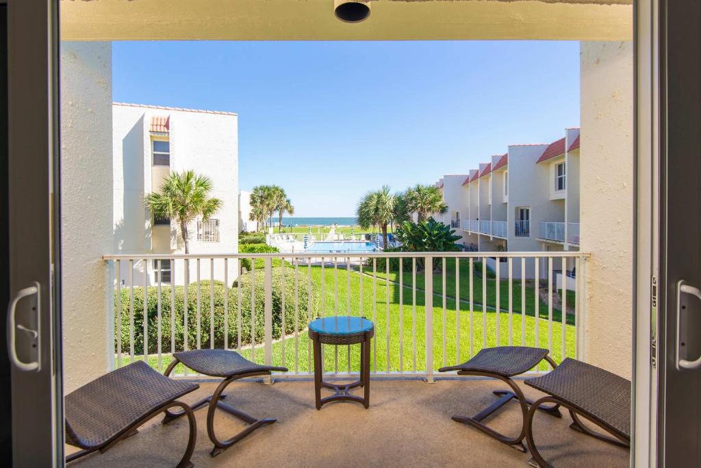 Habitación con vistas a un balcón con sillas y mesa. en Pier Point South Ocean View Townhouse Condo C-33, en St. Augustine Beach