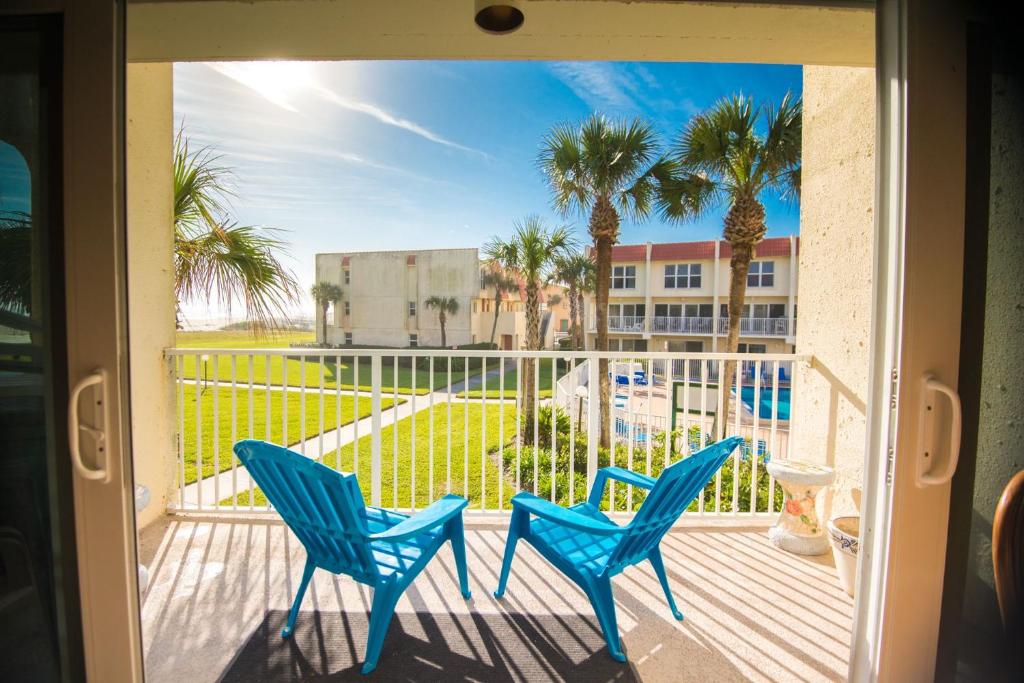 a balcony with two blue chairs and palm trees at Pier Point South Ocean View Condo B-14 in Saint Augustine Beach