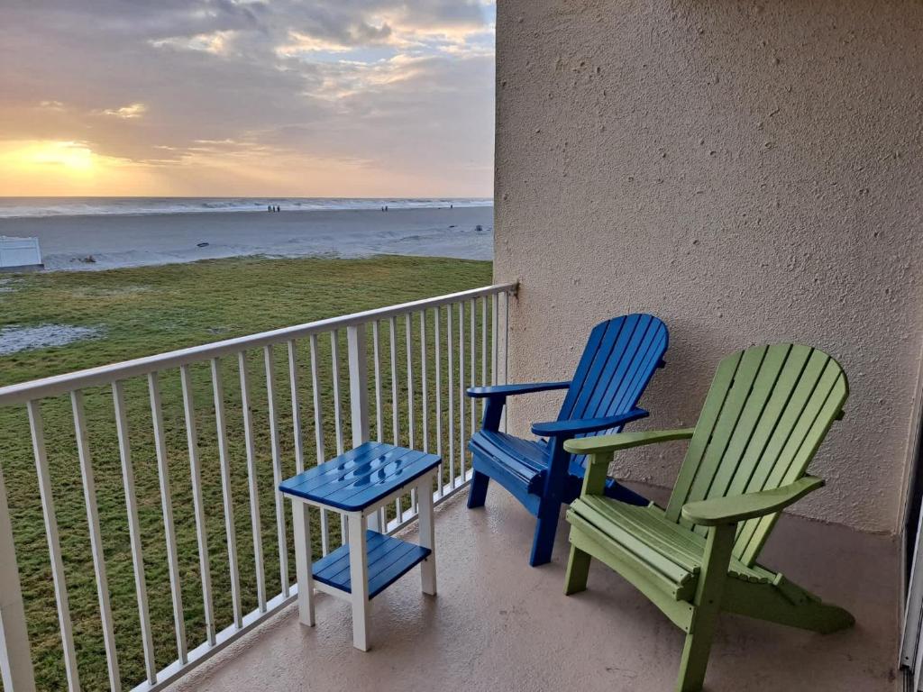 - deux chaises et une table sur un balcon avec vue sur la plage dans l'établissement Pier Point South Oceanfront Townhouse Condo A-6, à Saint Augustine Beach