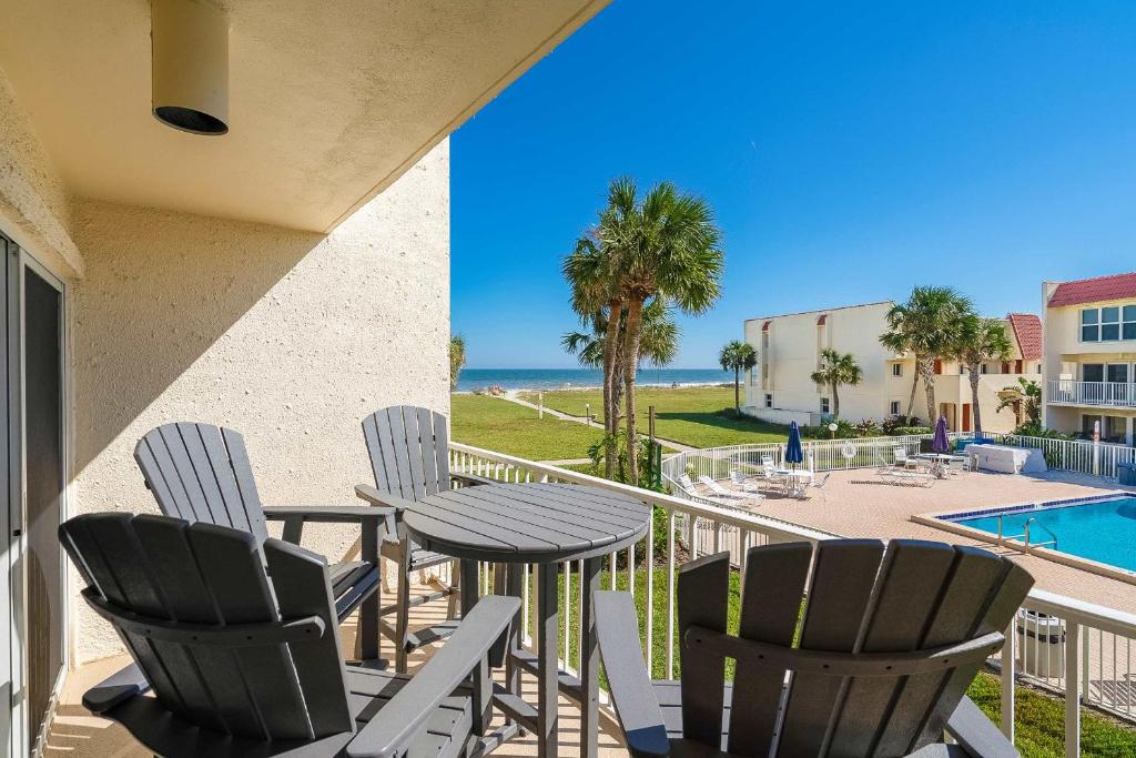 a balcony with chairs and a table and a pool at Pier Point South Ocean View Condo B-18 in St. Augustine