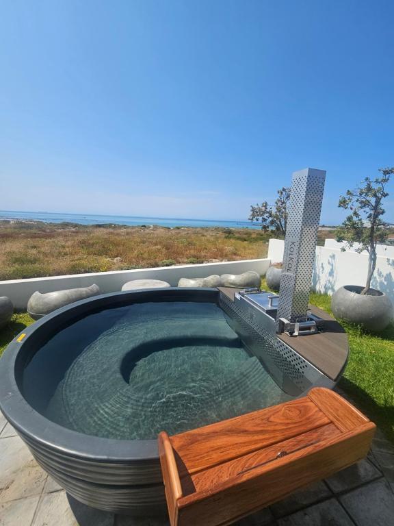 a jacuzzi tub with a wooden bench in it at Starfish Beach Villa in St. Helena Bay