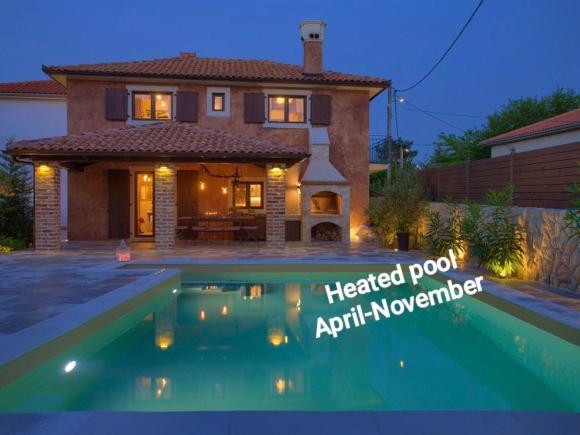 a house with a heated pool in front of a house at Holiday House Ursa in Krk