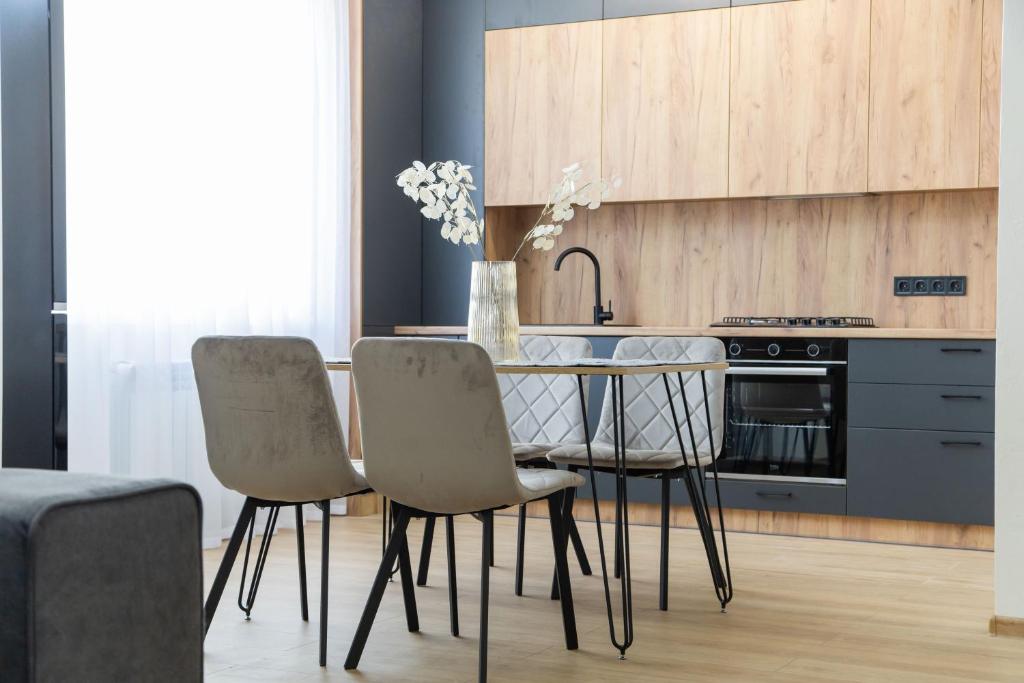 Una cocina con una mesa con sillas y una estufa. en Prime Business Apartments Cherkaska, en Petropavlovskaya Borshchagovka
