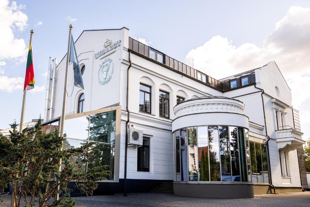 un edificio blanco con banderas delante en Embassy Studio 303, en Vilna