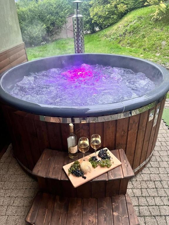 a hot tub with two glasses of wine and a table with two wine glasses at Słoneczny domek in Brenna