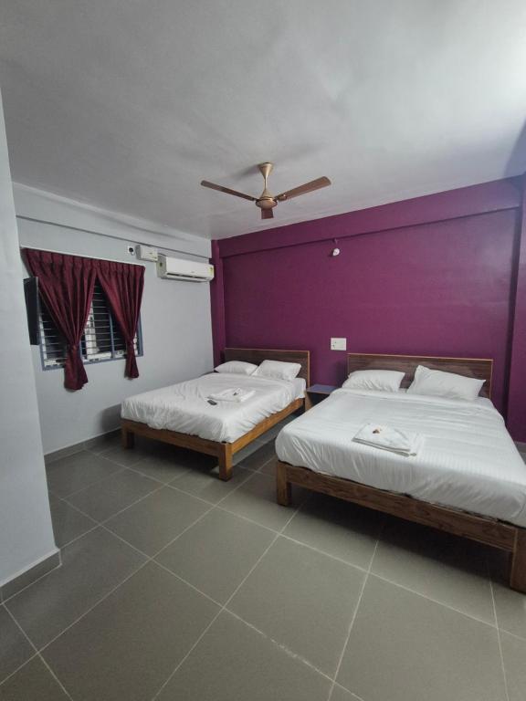 two beds in a room with purple and purple walls at KN Park in Tiruchirappalli