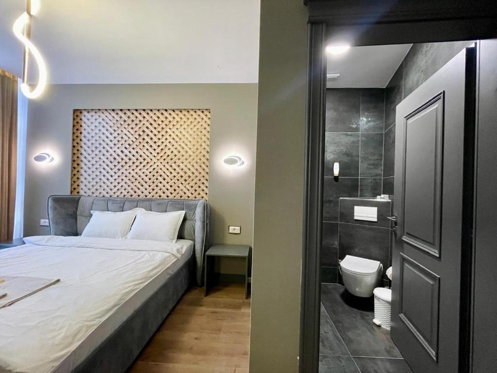 KukësにあるGRAND JNK Boutique Hotelのベッドのある寝室とトイレのある浴室