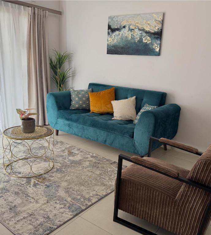 a living room with a blue couch and a table at The Fig Central Apartments in Gaborone