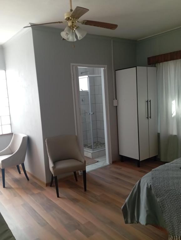 a bedroom with a bed and a chair and a fan at Yakhe self catering accommodation in Edenvale