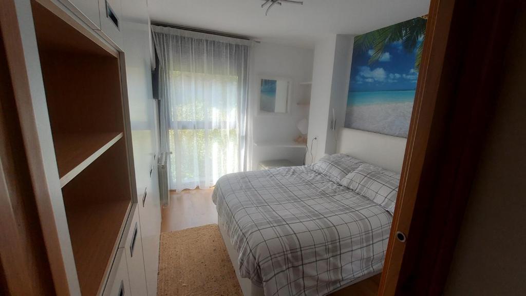 a small bedroom with a bed and a window at Apto playa Alojamientos Marte in Suances