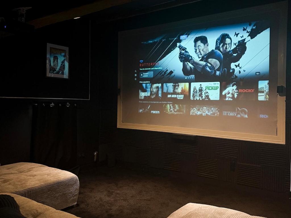 Una gran pantalla de proyección en una habitación con cama en Cinema Loft, en Elne