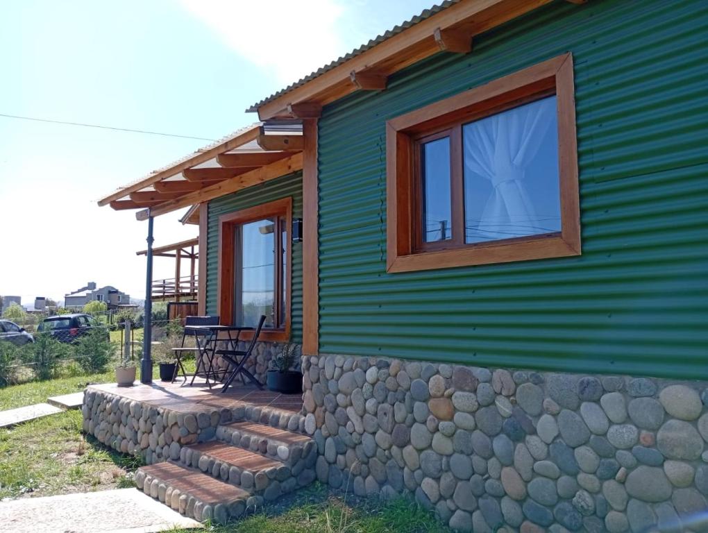 a green house with a stone wall and a window at El Cardon in Sierra de la Ventana
