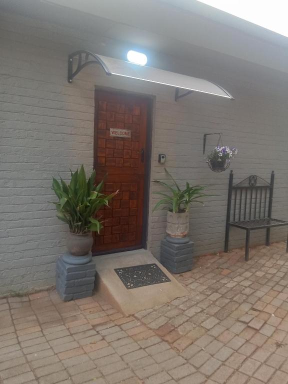 a front door of a house with two potted plants at Lourette se Plek in Sannieshof