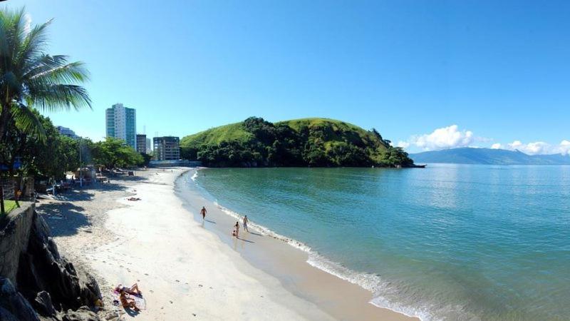 un grupo de personas en una playa cerca del agua en Apartamento Prainha perto de tudo pe na areia - 3 andar escada, en Caraguatatuba