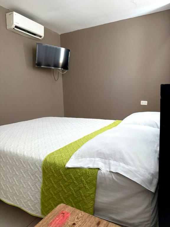 a bedroom with a bed with a television on the wall at hotel gloria del norte sas in Cartagena de Indias