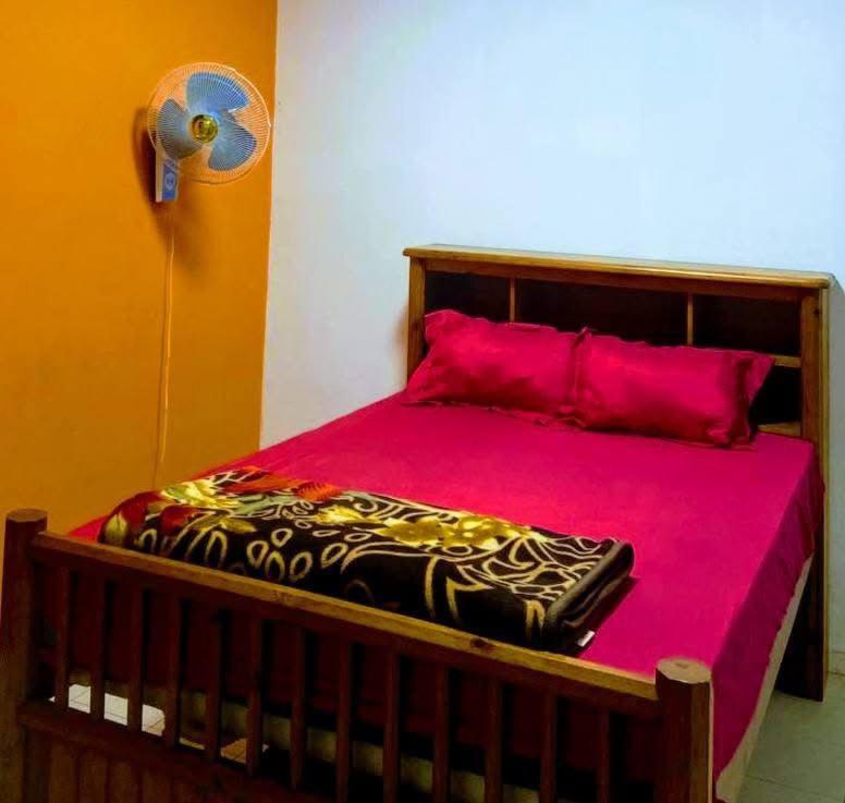 - un lit avec des draps roses et des oreillers rouges dans l'établissement Baobab immobilier Thiès, à Thiès