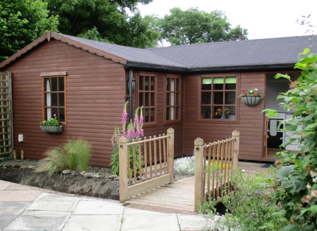 a small house with a wooden fence in front of it at The Garden Lodge in Llynclys